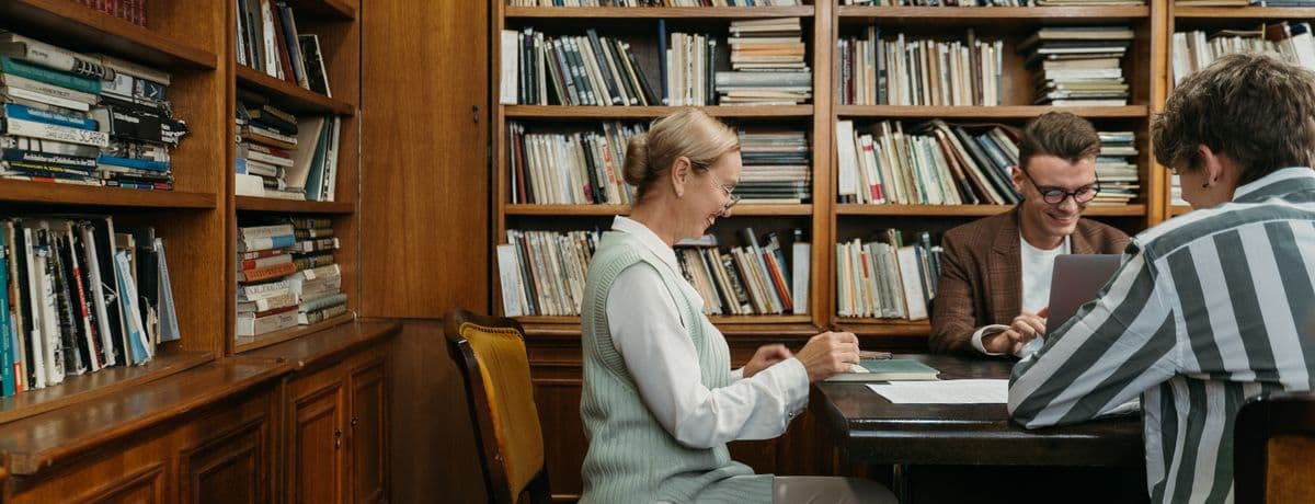 Editors working at a table in a book-lined library